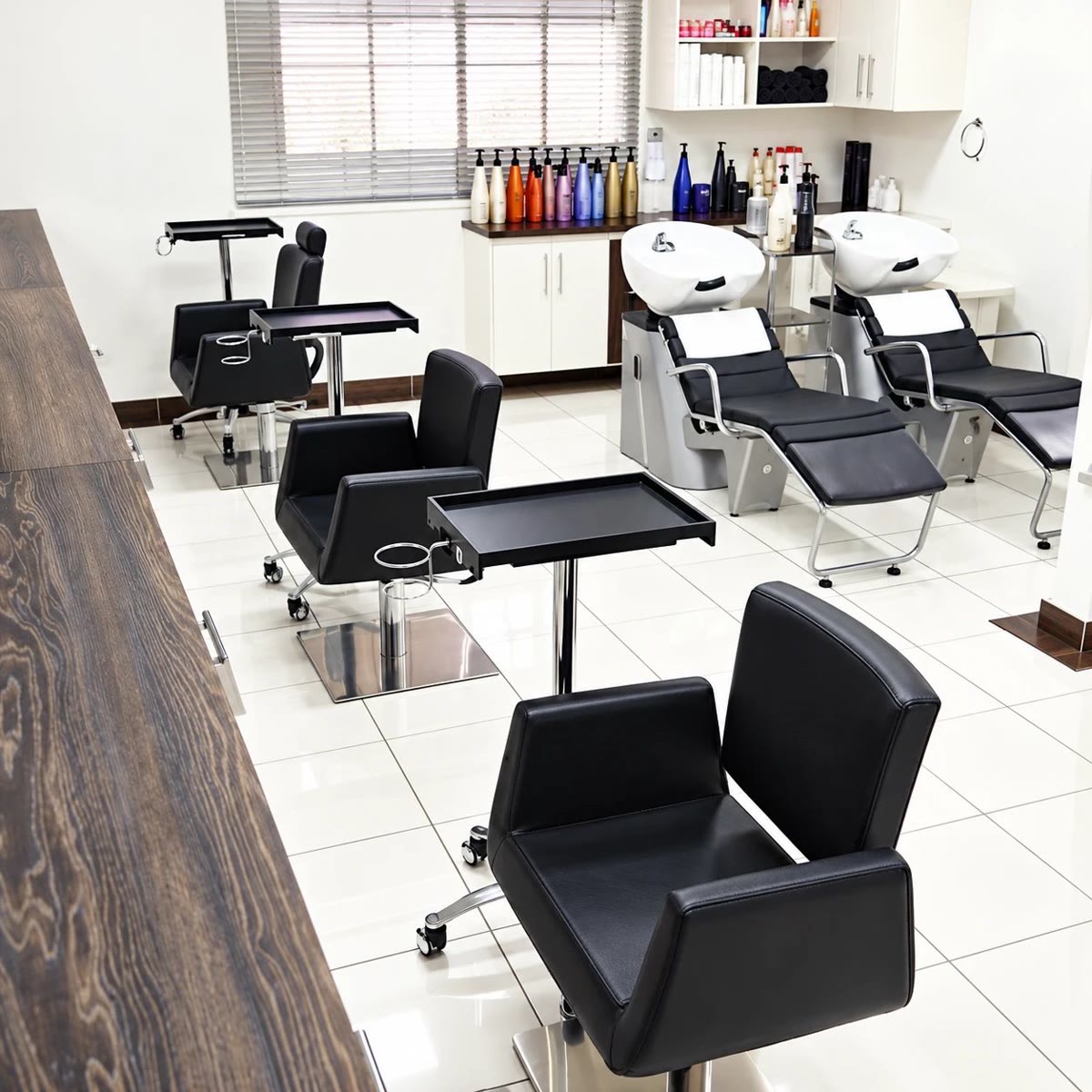 Salão Allure: azulejo branco, cadeiras de couro preto e bancada de madeira escura